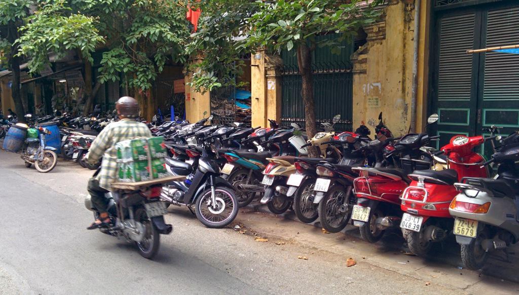 Many motorbikes taking up the sidewalk.