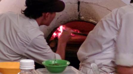 Placing pizza into the clay oven